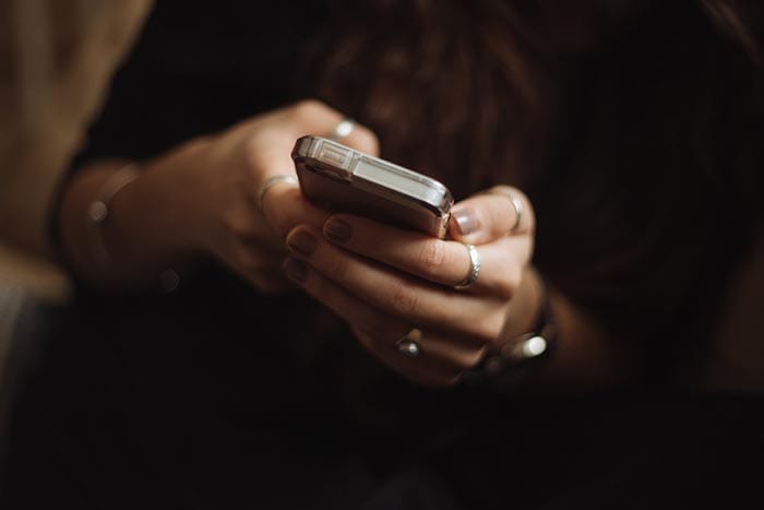 a woman with rings on her fingers holding an iphone