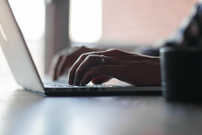 two hands typing on a laptop