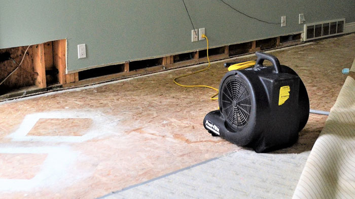 an industrial fan drying out water damage under a carpet