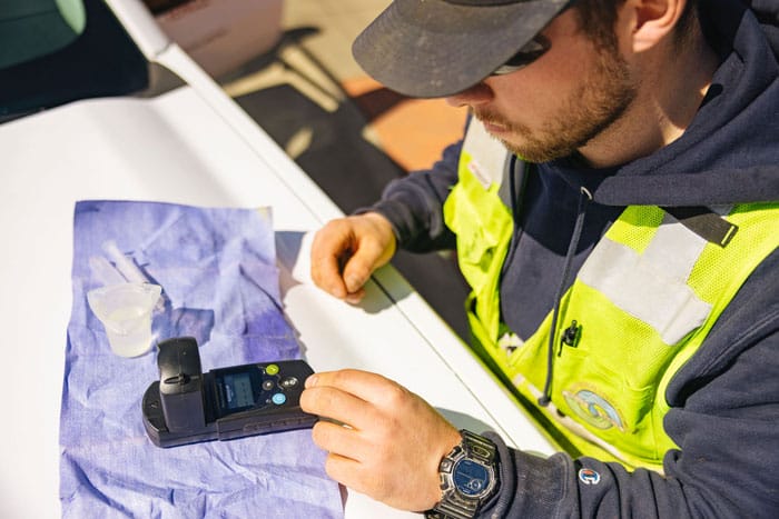 a worker testing the water quality with a remote-like gadget