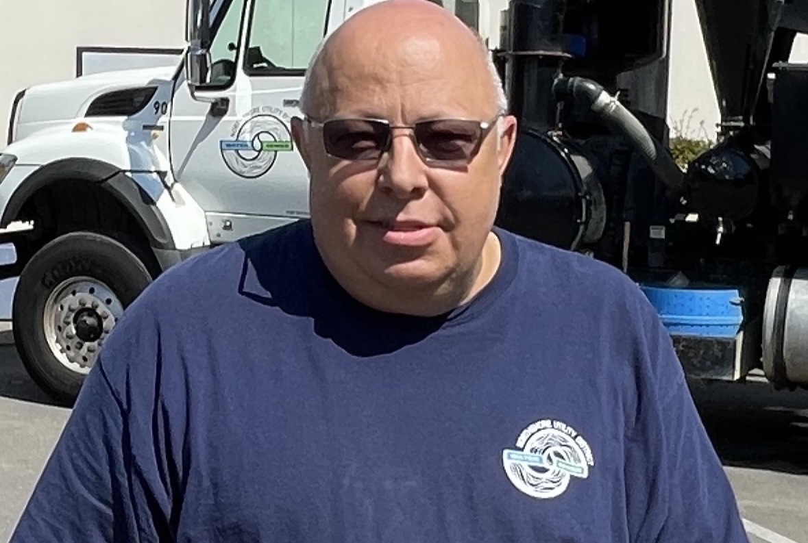 Bill, a bald man in a blue shirt, standing in front of a truck.